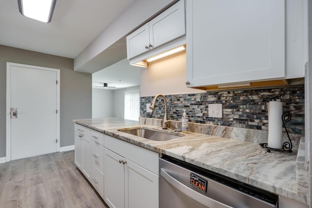 kitchen with light stone counters, a sink, backsplash, white cabinetry, and stainless steel dishwasher