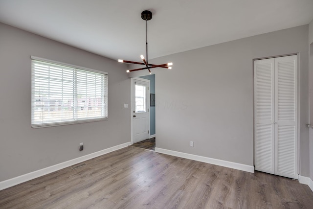 interior space featuring baseboards, visible vents, wood finished floors, and a chandelier