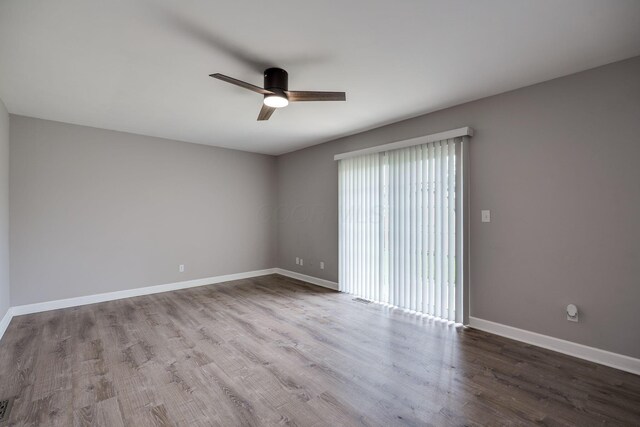 spare room featuring baseboards, ceiling fan, and wood finished floors