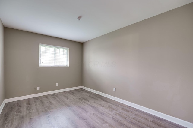 empty room with baseboards and light wood-style flooring