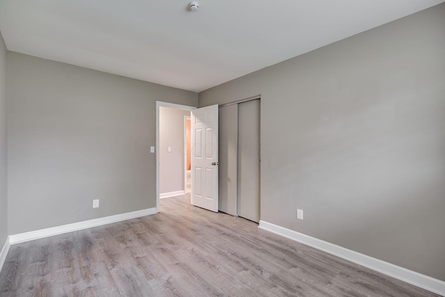 unfurnished bedroom with a closet, baseboards, and light wood-type flooring