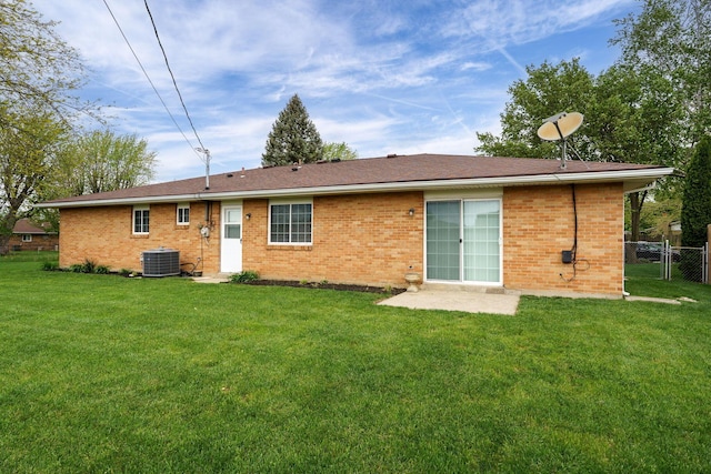 back of property with a lawn, brick siding, fence, and central air condition unit
