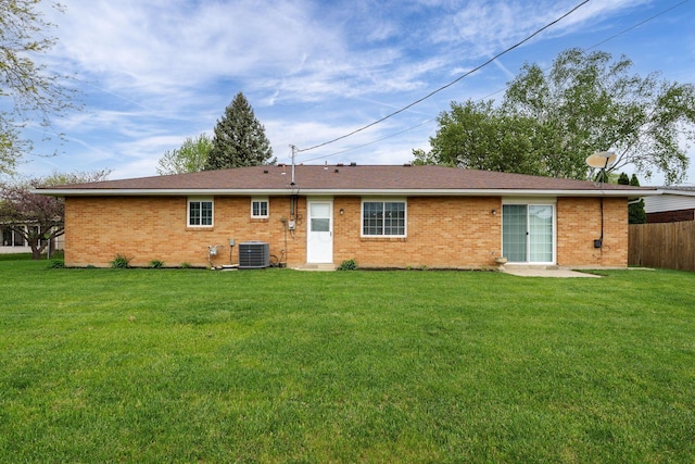 back of property with central air condition unit, fence, a yard, and brick siding