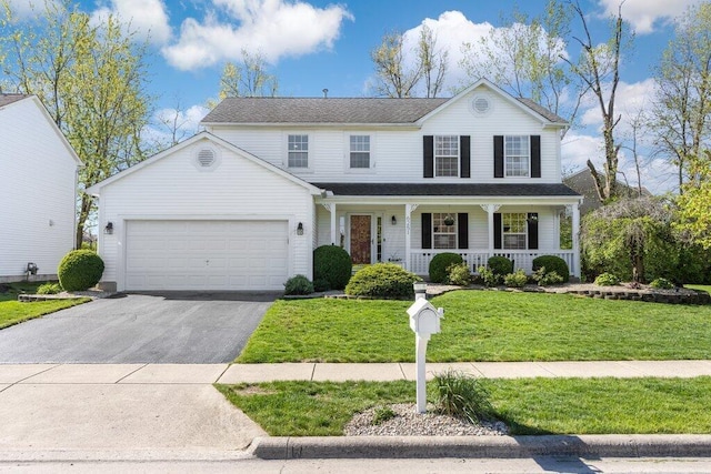 traditional-style house featuring covered porch, an attached garage, a front yard, and aphalt driveway