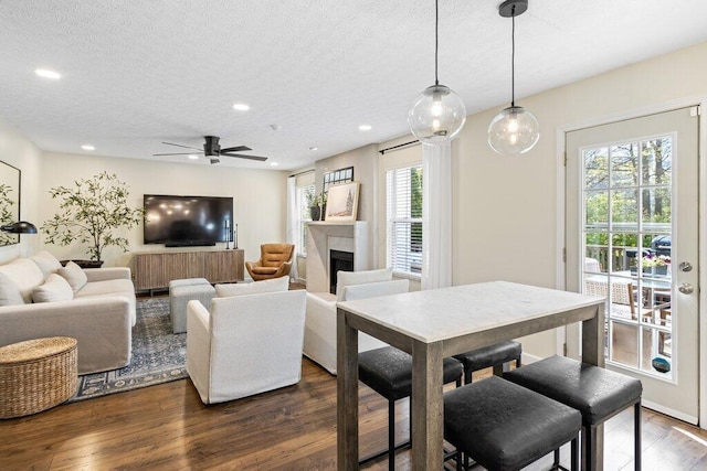 dining area with ceiling fan, a textured ceiling, a fireplace, dark wood finished floors, and recessed lighting