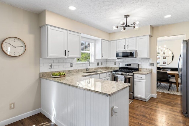 kitchen with white cabinetry, a sink, appliances with stainless steel finishes, and an inviting chandelier