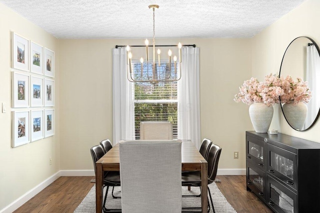 dining space featuring dark wood-style flooring, baseboards, a chandelier, and a textured ceiling