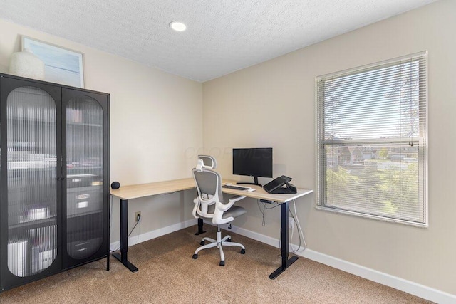 carpeted office featuring baseboards and a textured ceiling