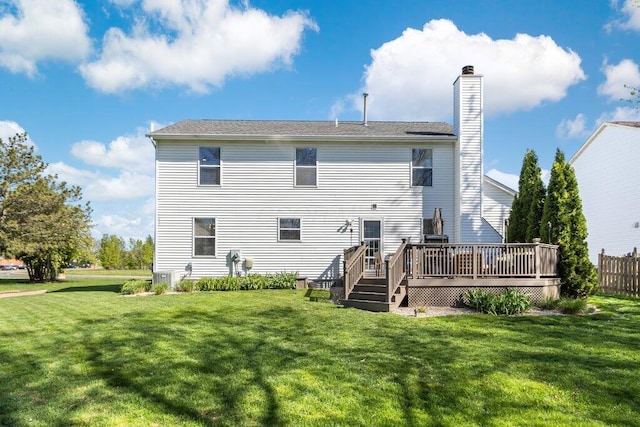 back of property with a chimney, a yard, and a deck