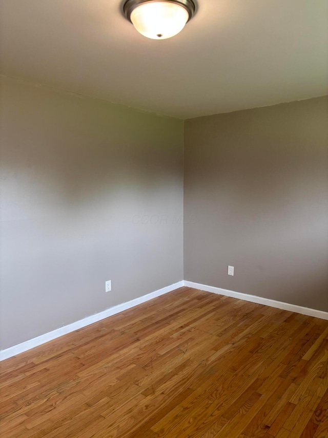 empty room with baseboards and wood finished floors
