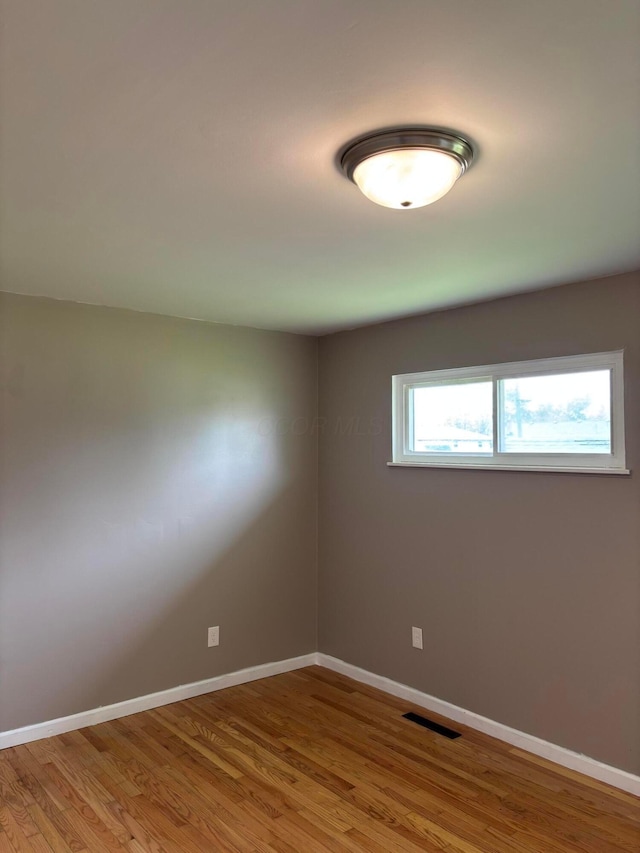 spare room featuring visible vents, baseboards, and wood finished floors