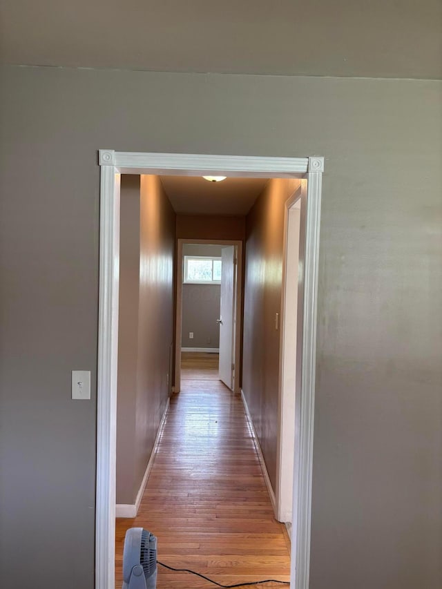 hall featuring baseboards and light wood-type flooring