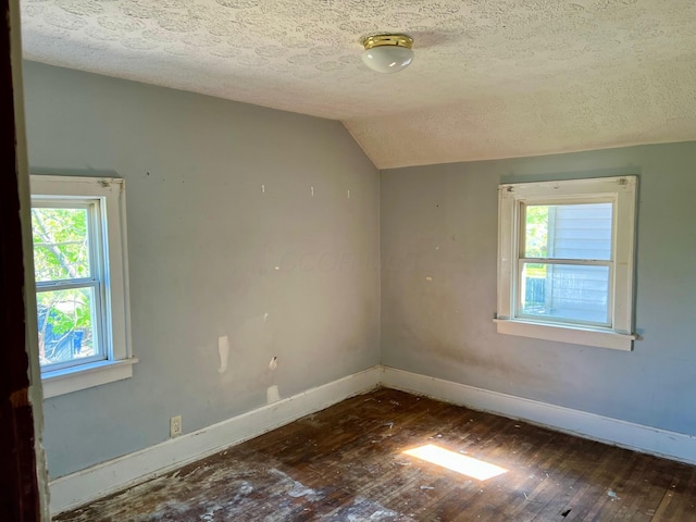 unfurnished room featuring a healthy amount of sunlight, baseboards, wood-type flooring, and a textured ceiling