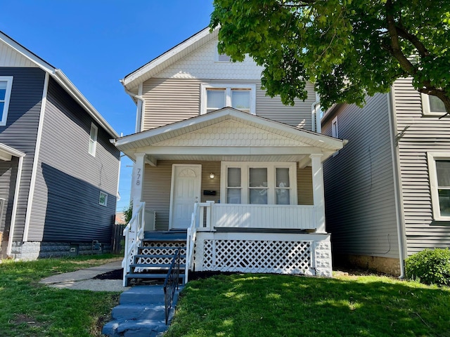 american foursquare style home with a front lawn and covered porch