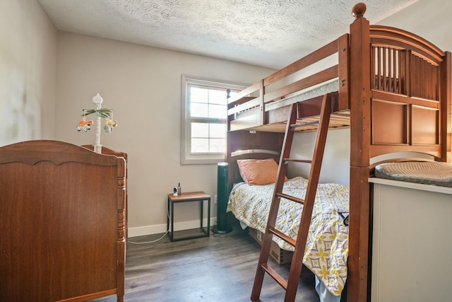 bedroom with baseboards, a textured ceiling, and wood finished floors