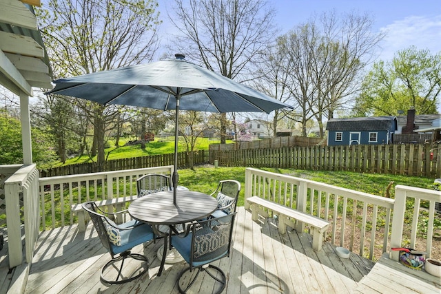 wooden terrace featuring a lawn, outdoor dining space, and a fenced backyard