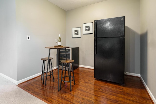 dining room featuring baseboards, beverage cooler, and wood finished floors
