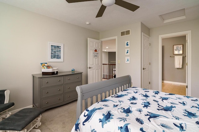 bedroom with visible vents, attic access, baseboards, and ceiling fan