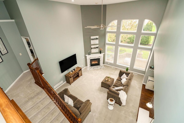 living room featuring baseboards, a glass covered fireplace, a high ceiling, and a wealth of natural light