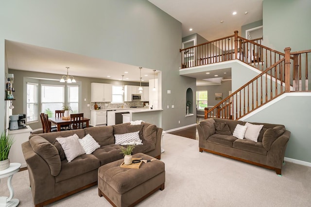 living area with an inviting chandelier, baseboards, stairway, and a healthy amount of sunlight