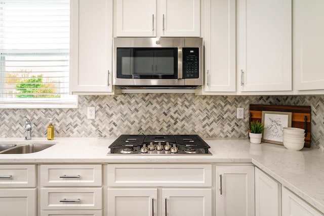 kitchen featuring backsplash, stainless steel appliances, white cabinetry, and a sink