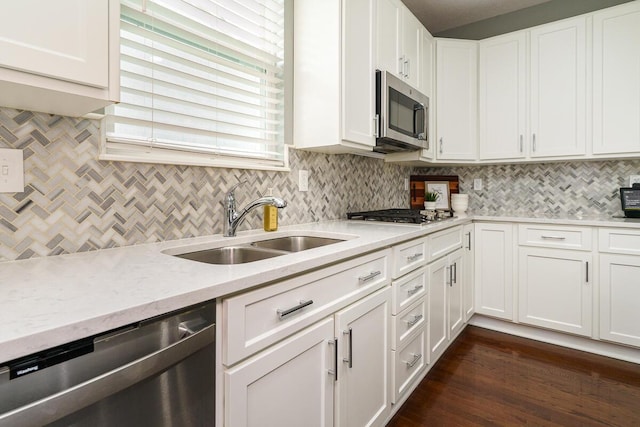 kitchen with a sink, white cabinetry, backsplash, and stainless steel appliances