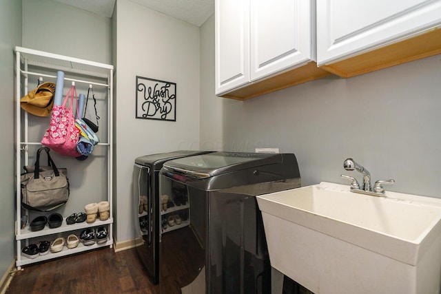clothes washing area featuring dark wood-style flooring, baseboards, a sink, cabinet space, and independent washer and dryer