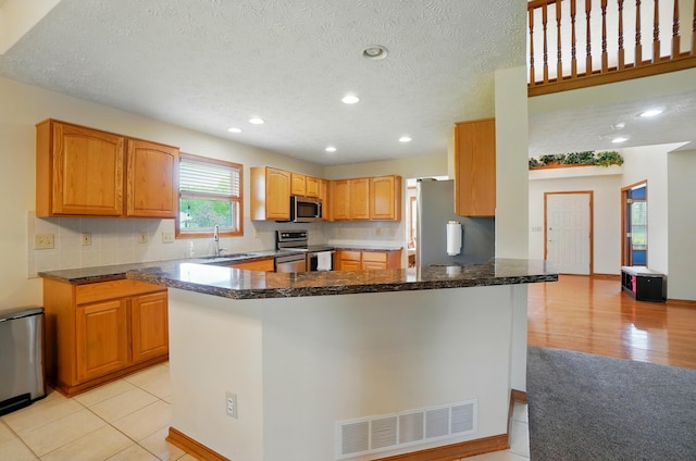 1775 Harrison Pond Dr, New Albany, OH 43054 - kitchen with stainless steel appliances, dark stone countertops, a sink, recessed lighting, and a peninsula