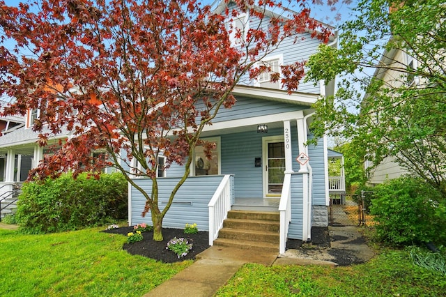 view of front of property featuring fence, covered porch, and a front yard