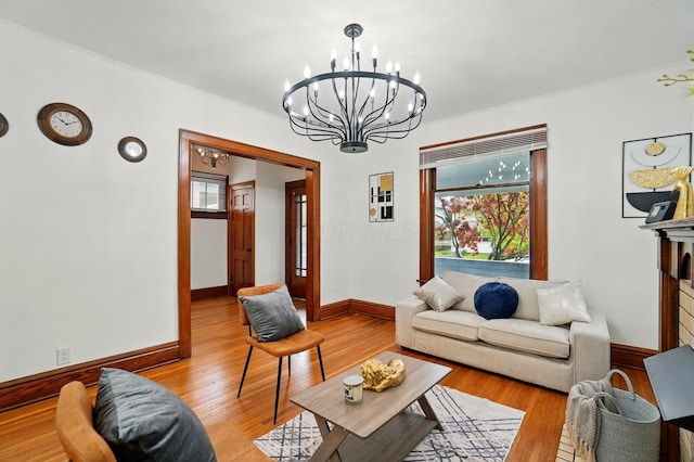 living room featuring baseboards, a notable chandelier, and light wood-style flooring