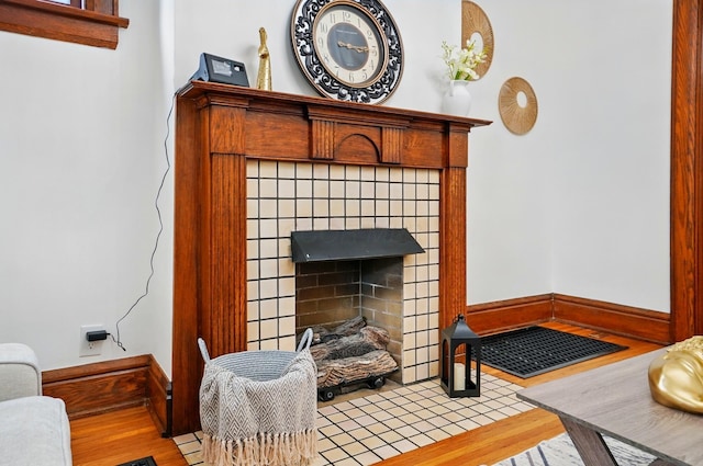 living area featuring baseboards, wood finished floors, and a tile fireplace