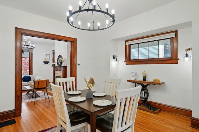 dining space with baseboards, visible vents, light wood-type flooring, and a notable chandelier