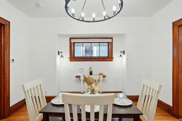 dining room with baseboards, a notable chandelier, and light wood-style floors