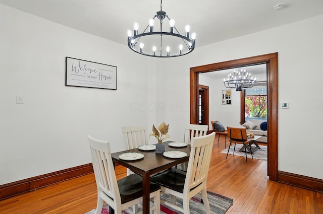 dining space with light wood-style floors, baseboards, and a chandelier
