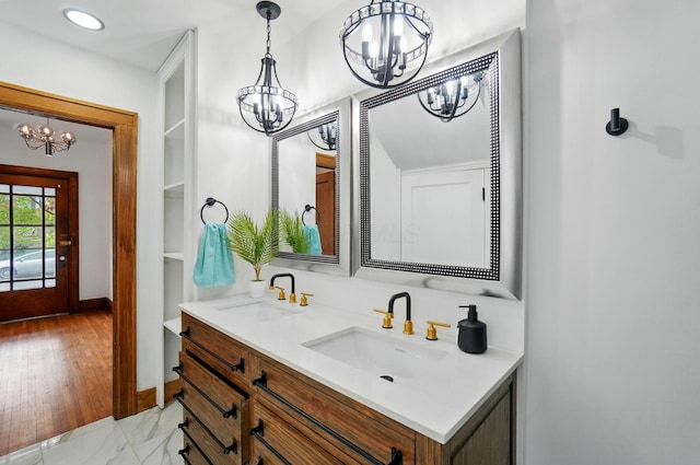 bathroom with an inviting chandelier, a sink, baseboards, and double vanity