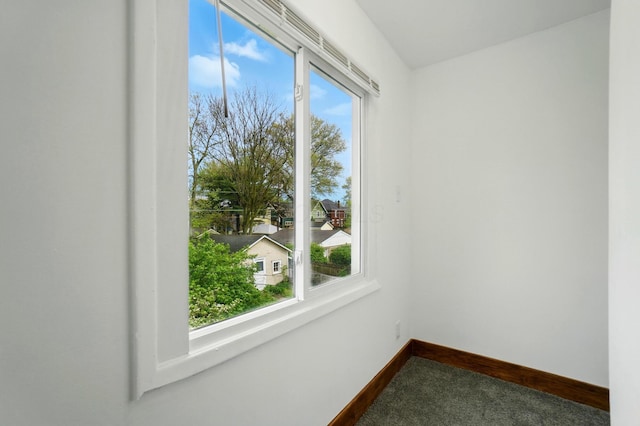 spare room featuring baseboards and dark colored carpet