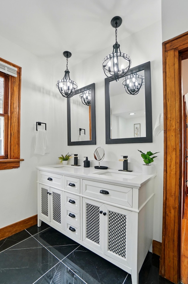 bathroom featuring baseboards, a sink, a chandelier, and double vanity