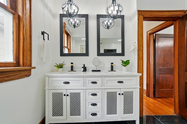 full bath featuring double vanity, a sink, and a notable chandelier