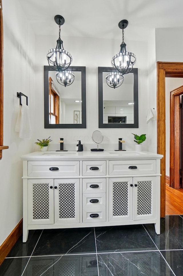 bathroom featuring double vanity, a sink, baseboards, and a chandelier