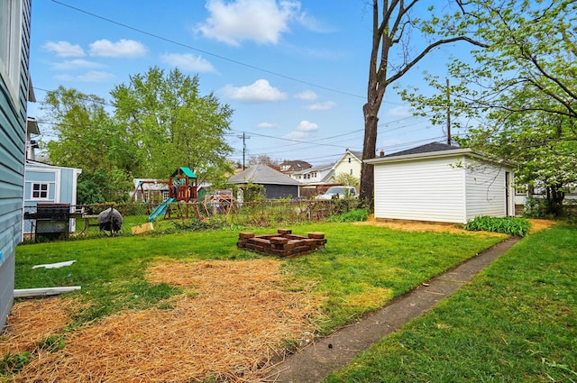 view of yard featuring a playground, fence, and an outbuilding