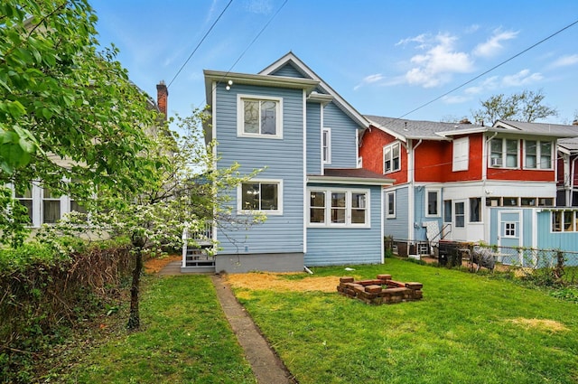rear view of house featuring a lawn and fence