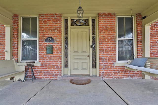 entrance to property with a porch and brick siding