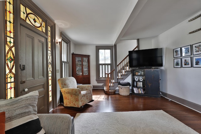 living area with baseboards, stairs, and wood finished floors