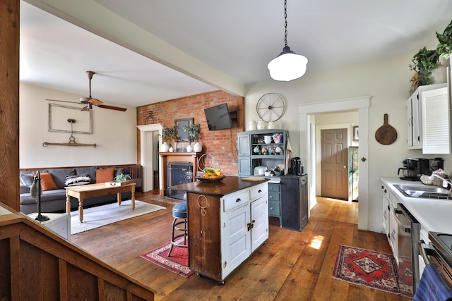 kitchen featuring a ceiling fan, brick wall, hardwood / wood-style floors, a kitchen bar, and a sink