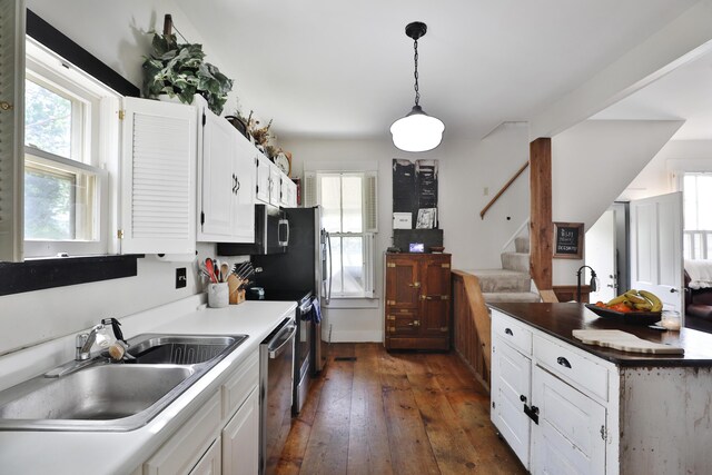 kitchen with dark wood-style floors, white cabinetry, a sink, appliances with stainless steel finishes, and a wealth of natural light
