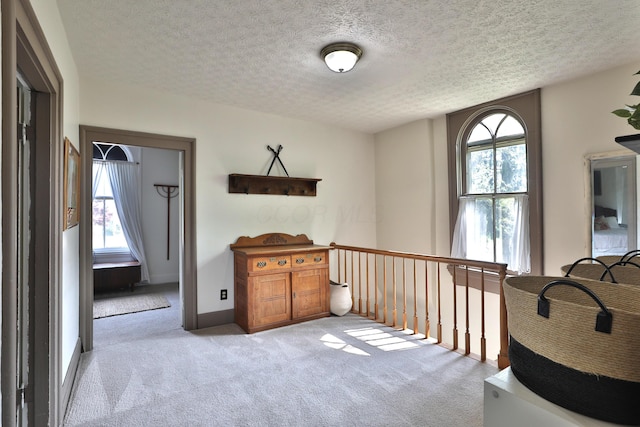 hallway with a textured ceiling and carpet