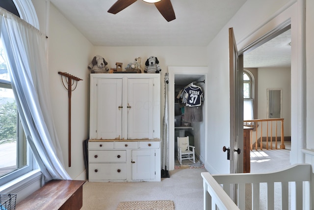 bedroom with a ceiling fan, multiple windows, and light carpet