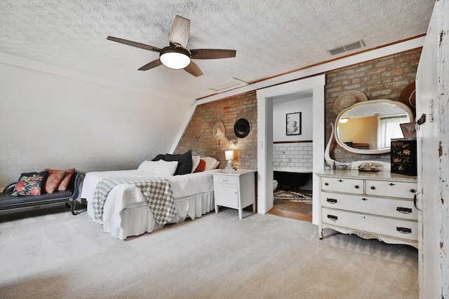 bedroom featuring visible vents, ensuite bathroom, light colored carpet, a textured ceiling, and a ceiling fan