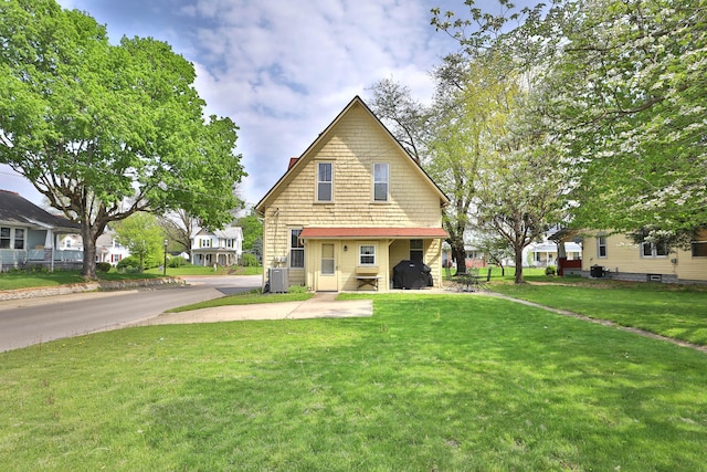 view of front of property with central AC unit and a front lawn
