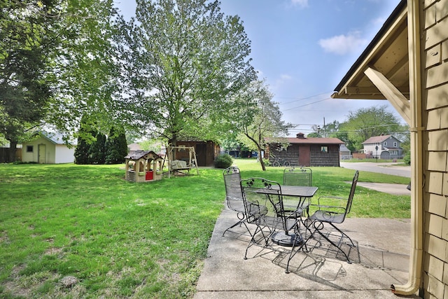 view of yard featuring outdoor dining space, an outdoor structure, and a patio area